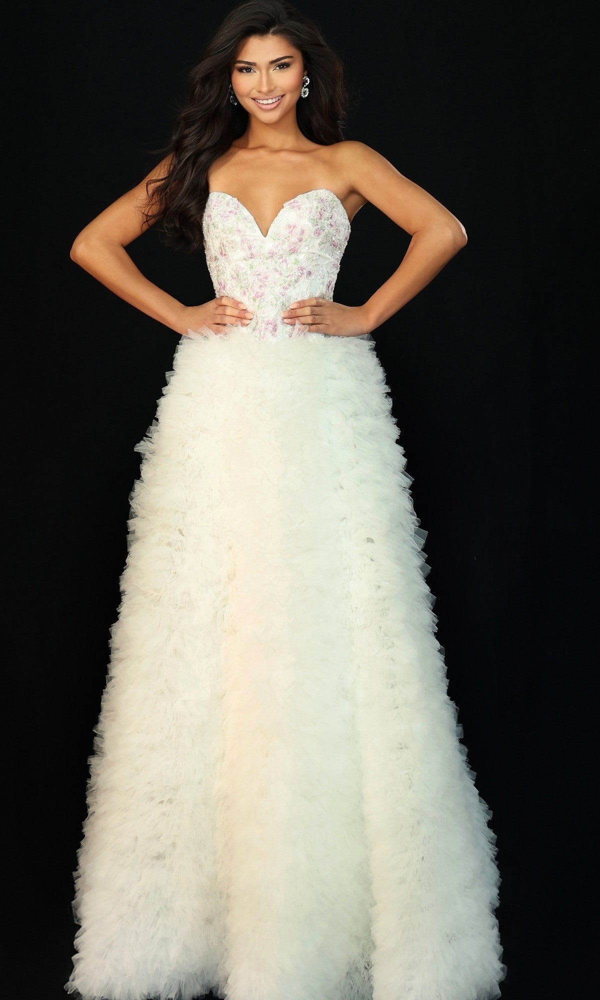 A woman poses against a black background wearing the Jovani 45636 long prom dress, featuring a strapless white design with a beaded bodice and textured ruffled A-line skirt.